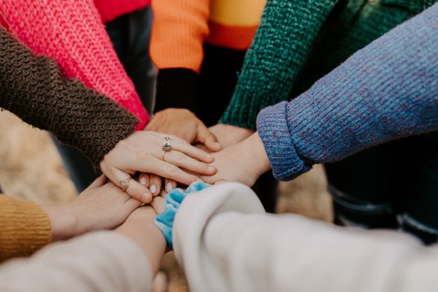 Close-up of several hands overlapping from people stood in a circle  