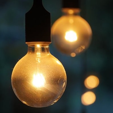 Close-up of two light bulbs shining against a dark background